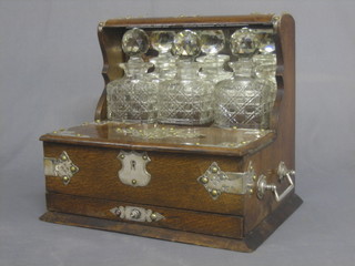 An oak and silver plated 3 bottle tantalus frame with 3 cut glass spirit decanters (no key)