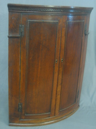 A 19th Century oak hanging corner cabinet with moulded and dentil cornice, the interior fitted shelves enclosed by panelled doors 31"