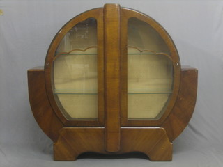 An Art Deco walnut circular shaped display cabinet, the interior fitted shelves enclosed by glazed panelled doors