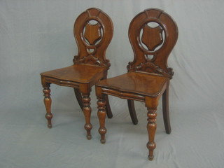 A pair of Victorian mahogany hall chairs with solid seats and shield shaped backs