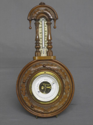 An aneroid barometer with silvered dial contained in a carved walnut case