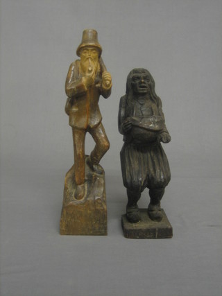 A carved wooden figure of a standing man smoking a pipe 10" and a carved candle holder in the form of a crouching man 12"