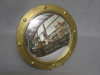 A circular convex wall mirror contained in a brass port hole style frame 10"