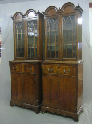 A pair of Georgian style inlaid mahogany secretaire bookcase cabinets, the upper section with domed double cornice, the interior  fitted adjustable shelves enclosed by astragal glazed panelled doors, the base fitted a secretaire drawer above a double cupboard, raised on splayed bracket feet 26"