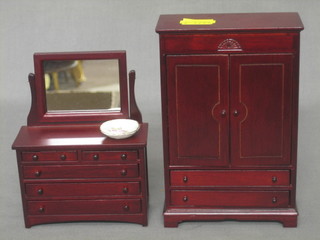 A dolls house mahogany finished wardrobe enclosed by panelled doors together with a dressing chest