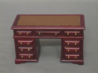 A dolls house mahogany pedestal desk fitted 1 long drawer flanked by 8 short drawers, raised on bracket feet 5"