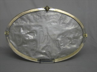 An oval bevelled plate wall mirror contained in a decorative gilt metal frame surmounted by a figure of a rams mask 33"