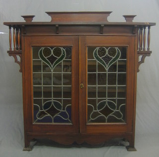 An Edwardian Art Nouveau mahogany display cabinet fitted adjustable shelves enclosed by lead glazed panelled doors and with turned column decoration to the sides 53"