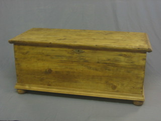 A Continental stripped and polished pine coffer with hinged lid and iron drop handles, raised on bun feet 46"