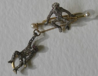 A decorative gold bar brooch in the form of a seated monkey and a swinging monkey set pearls, rubies and diamonds