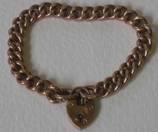 A heavy gold curb link bracelet with heart shaped padlock clasp