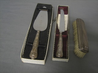 A silver backed clothes brush, a silver handled cake knife and a silver handled bread knife