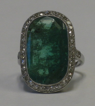 A lady's white gold dress ring set a cabouchon cut emerald supported by numerous diamonds