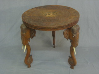 A circular carved Eastern hardwood occasional table raised on elephant supports 24"