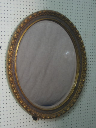 An oval bevelled plate wall mirror contained in a decorative gilt frame 24"
