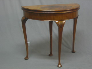 A 1930's Queen Anne style figured walnut demi-lune card table raised on cabriole supports 30"