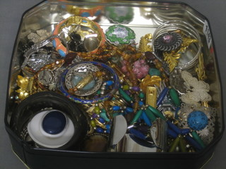 A metal tin containing a collection of costume jewellery