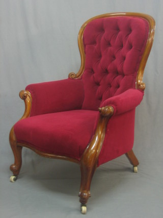 A Victorian mahogany show frame armchair upholstered in red buttoned material on cabriole supports