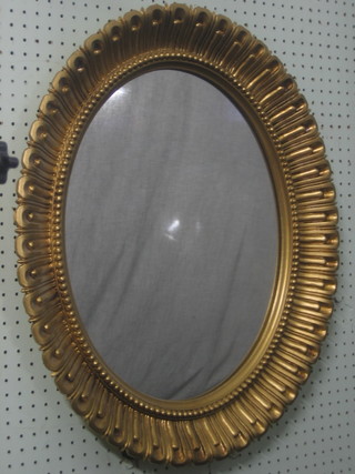 An oval wall mirror contained in a decorative gilt frame 26"