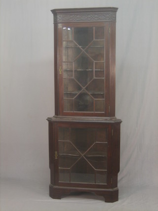 A Chippendale style mahogany double corner cabinet with moulded cornice and blind fret work frieze, the upper section fitted shelves enclosed by astragal glazed doors, the base fitted shelves enclosed by astragal glazed panelled doors, raised on bracket feet 29"