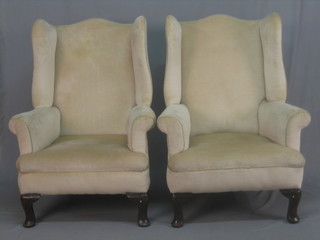 A pair of oak framed winged armchairs, upholstered in cream material