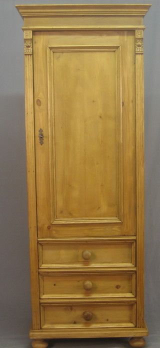 A stripped and polished pine Sentry box style cupboard fitted shelves enclosed by panelled doors, the base fitted 3 drawers, raised on bun feet 27"