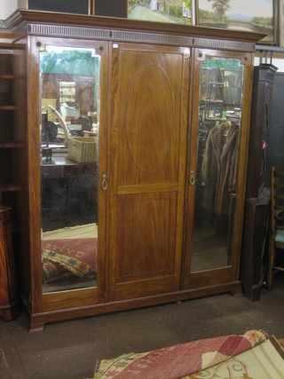 An Edwardian triple wardrobe with moulded cornice, the centre section enclosed by a panelled door flanked by a pair of bevelled plate mirrored doors, raised on bracket feet 72"