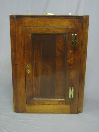 A Georgian oak hanging corner cabinet the interior fitted shelves enclosed by a panelled door 26"