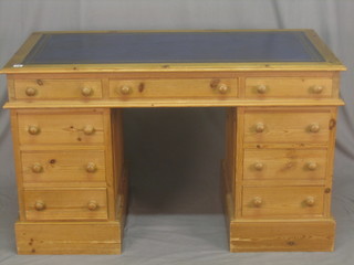 A pine kneehole pedestal desk with inset tooled green leather writing surface, fitted 1 long and 8 short drawers 49"