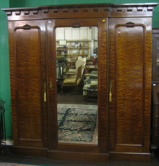 A Victorian mahogany triple breakfront wardrobe with moulded and dentil cornice, the centre section enclosed by a mirrored panelled door flanked by a pair of cupboards enclosed by panelled doors, raised on a platform base 83"