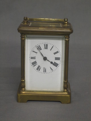 A carriage clock with enamelled dial and Roman numerals contained in a gilt metal case