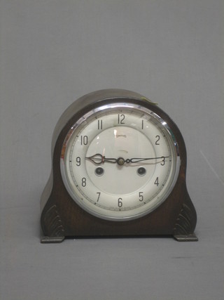 A striking mantel clock with silvered dial and Roman numerals contained in an oak shaped case