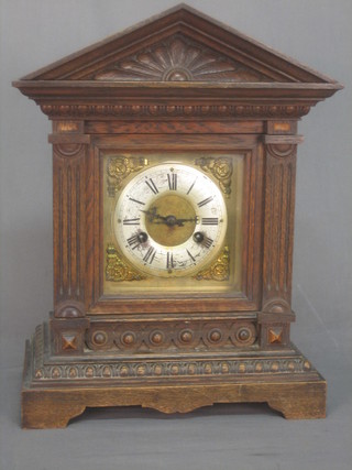 An Edwardian Continental striking bracket clock with brass dial, solar chapter ring and Roman numerals contained in a carved oak case