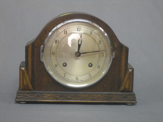 A 1930's chiming mantel clock with silvered dial and Arabic numerals contained in an oak arch shaped case