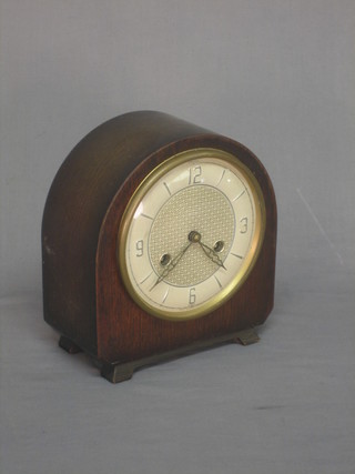 A 1950's striking mantel clock with silvered dial contained in an oak arched shaped case