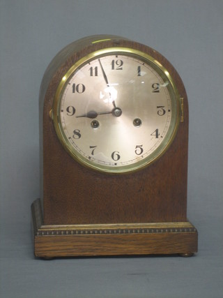 A 1930's 8 day striking mantel clock with silvered dial and Arabic numerals contained in an oak arch shaped case