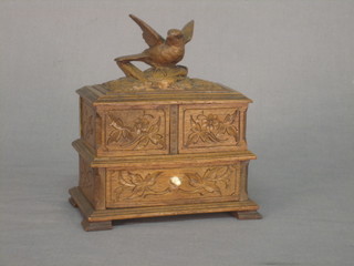 A Continental carved wooden jewellery box surmounted by a figure of a bird with section to the side, the base fitted a drawer 6"