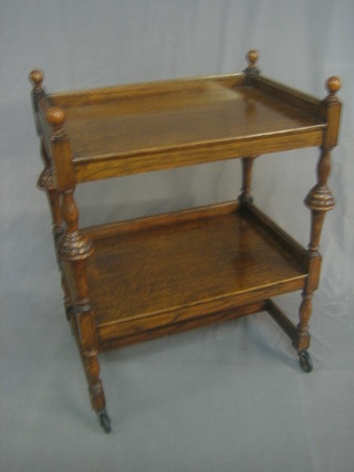 An oak 2 tier tea trolley raised on turned and block supports 24"