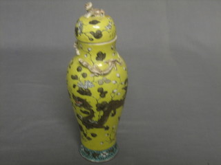 An Oriental yellow glazed club shaped urn and cover decorated dragons 11"