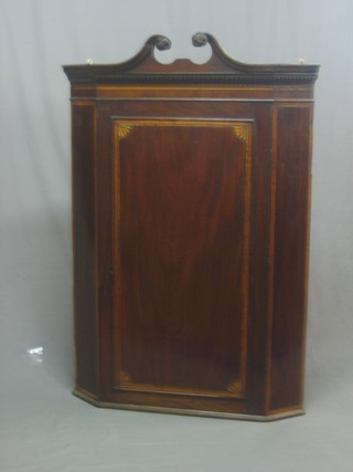 A Georgian inlaid mahogany hanging corner cabinet with broken pediment and dentil cornice, the interior fitted shaped shelves enclosed by a panelled door 34"