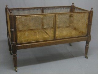 A Georgian mahogany cot with caned panelled sides, raised on turned supports 47"
