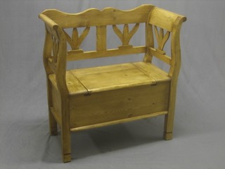 A Continental stripped and polished pine settle with pierced back, the seat with hinged lid 34"