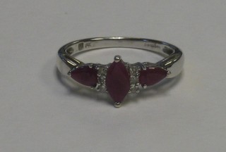 A lady's 9ct white gold dress ring set a boat shaped cut ruby supported by 2 rubies and 3 diamonds to the shoulders