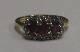 A 9ct gold dress ring set 3 oval red stones supported by diamonds