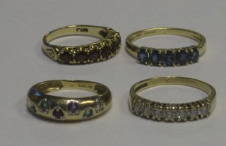 A 9ct gold half eternity ring set blue stones, a 9ct gold dress ring set white stones, a 9ct gold dress ring set red stones and a 9ct gold ring set green and red stones