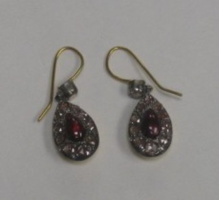 A pair of gold earrings set cabouchon cut garnets and diamonds