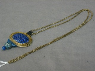 A gilt pierced metal and enamelled pendant hung on a gold chain