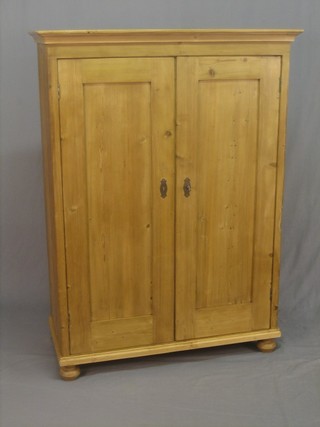 A Continental pine cabinet fitted shelves and enclosed by panelled doors, raised on bun feet 40"