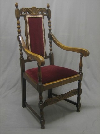 A carved oak open arm carver chair with upholstered seat and back, raised on turned and block supports