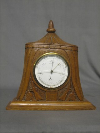 An aneroid barometer by Chambers contained in a carved oak Trench Art case decorated helmets and rifles 12"